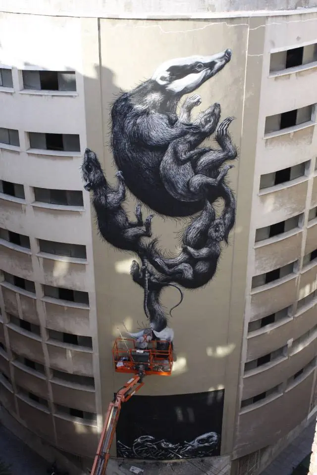 Completed animal mural across the curved facade, with the lift still at its base